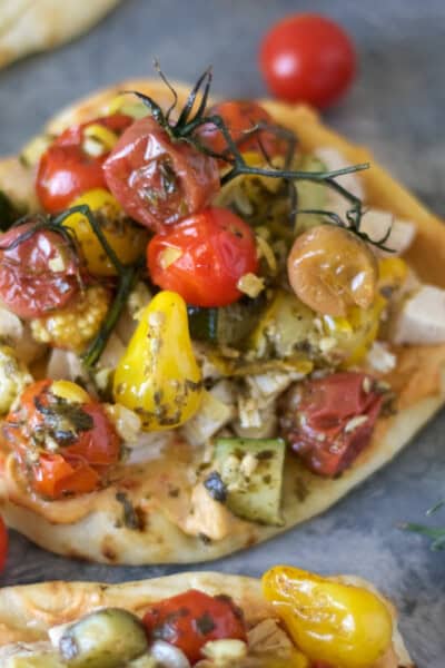 Mini naan topped with hummus, chicken and roasted tomatoes, zucchini and corn tossed in pesto.
