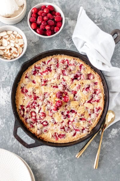 Cranberry Almond Cake in a cast iron skillet topped with three sugared cranberries.