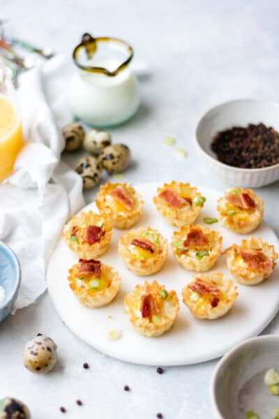 Baked Quail Egg Bites in phyllo shells topped with bacon and scallions.