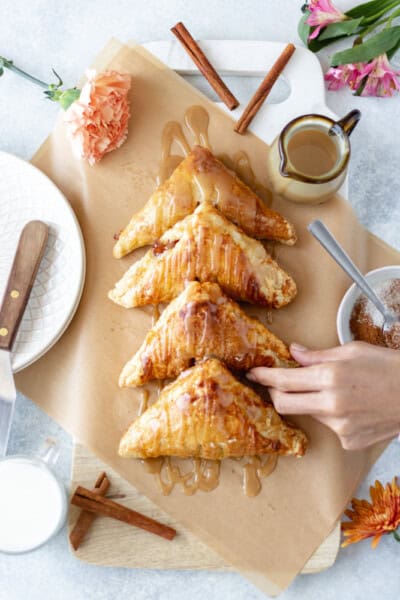 A hand grabbing a Baked Apple Turnover.