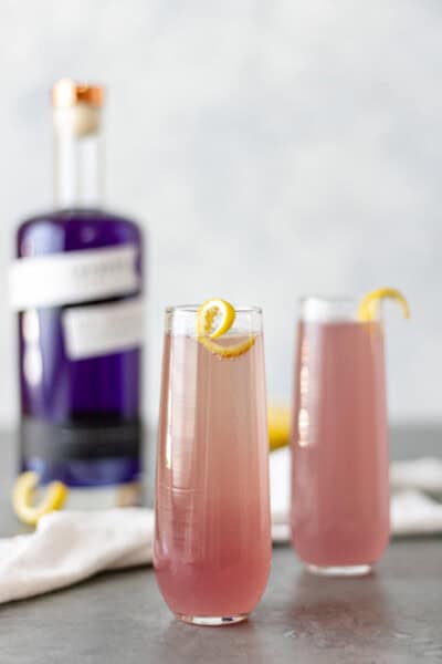 A French 75 Cocktail with Empress Gin, in two glass flutes, along side a bottle of Empress Gin.