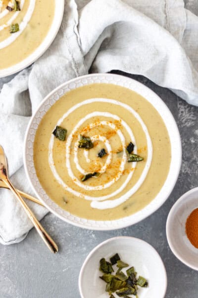 Two bowls of Roasted-Poblano Potato Soup topped with diced poblanos, sour cream and cayenne pepper.