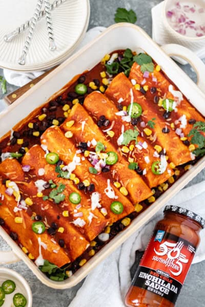 Chicken enchiladas covered in red enchilada sauce, corn, black beans, onion, jalapeño slices, dairy-free sour cream and fresh cilantro.