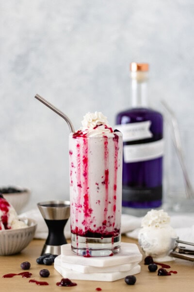 Mixed-Berry Ice Cream Shake in a glass topped with coconut whipped cream.