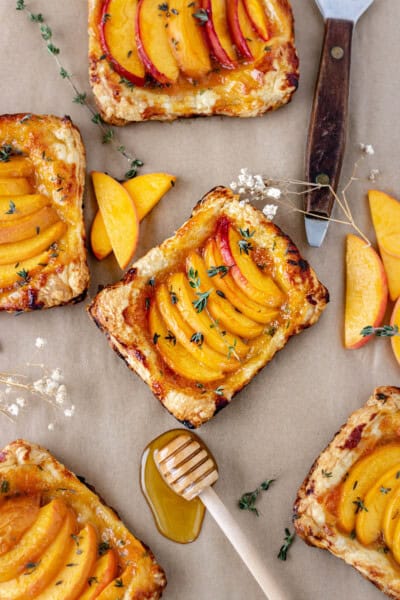 Five mini peach tarts on parchment paper.