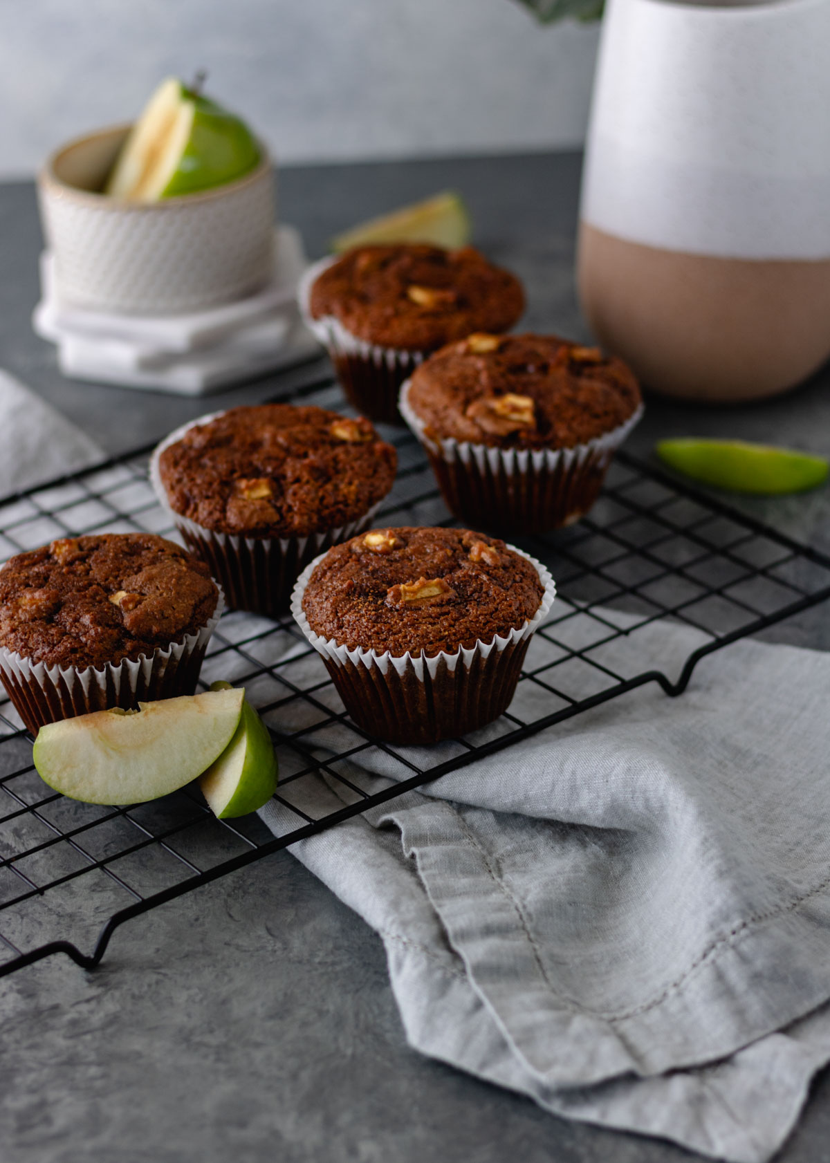 A wire rack full of baked Apple-Cinnamon-Zucchini Muffins with Cinnamon Sugar Topping and Granny Smith apple slices.